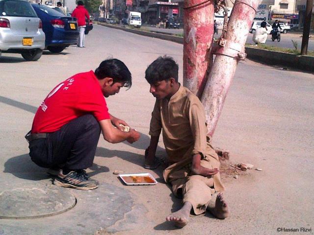 A waiter at a restaurant buys food and feeds a disabled homeless man with his own hands in Karachi, Pakistan.