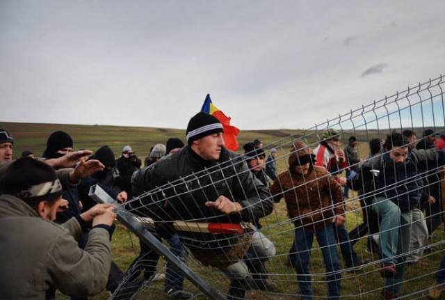 Romanian protesters tear down the fence of the exploring perimeter of US energy giant Chevron in Pungesti, Romania on December 7, 2013.